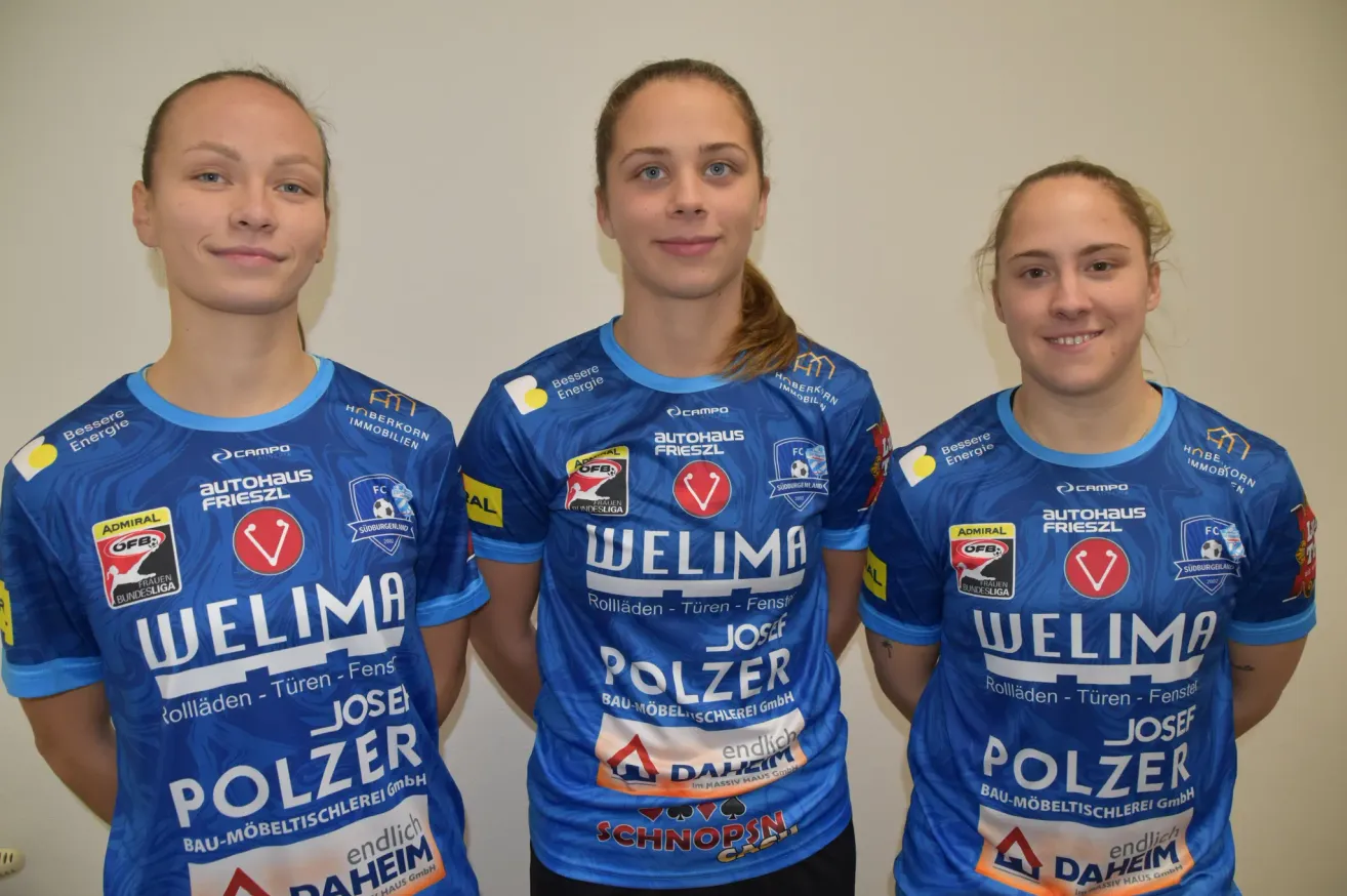 Drei Frauen in passenden blauen Trikots mit dem Wort 'POLZER' und Logos für 'AUTOHAUS FRIESZL', 'WELLIMA' und 'SCHNOPSN' stehen lächelnd zusammen. Die Frau in der Mitte hat eine Pferdeschwanzfrisur.