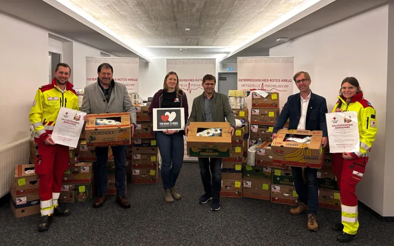 Vier Personen stehen vor einer großen Menge Bananen. Drei Männer und eine Frau. Alle lächeln und schauen in die Kamera.