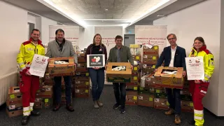 Vier Personen stehen vor einer großen Menge Bananen. Drei Männer und eine Frau. Alle lächeln und schauen in die Kamera.