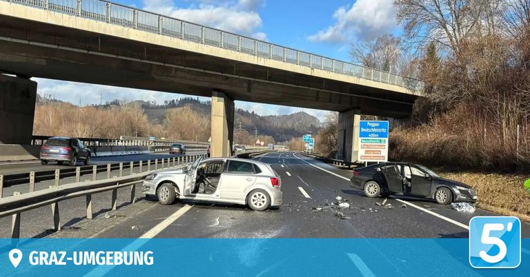 Zwei Autos sind auf einer Autobahn mit einer Überführung darüber beschädigt. Die Autos befinden sich auf gegenüberliegenden Seiten, und Trümmerteile sind auf der Straße verstreut. Ein Schild befindet sich rechts, und ein Berg ist im Hintergrund.