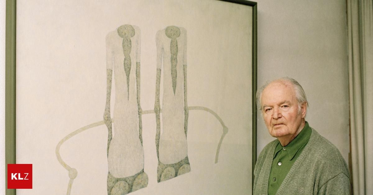 Ein älterer Mann steht vor einem großen Gemälde mit zwei abstrakten Figuren mit länglichen Körpern und Gesichtern, gekleidet in langen Kleidern. Das Gemälde hat einen grünen Rahmen.