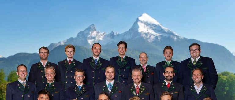 Eine Gruppe von Männern in traditioneller Kleidung, die vor einem Bergpanorama stehen.