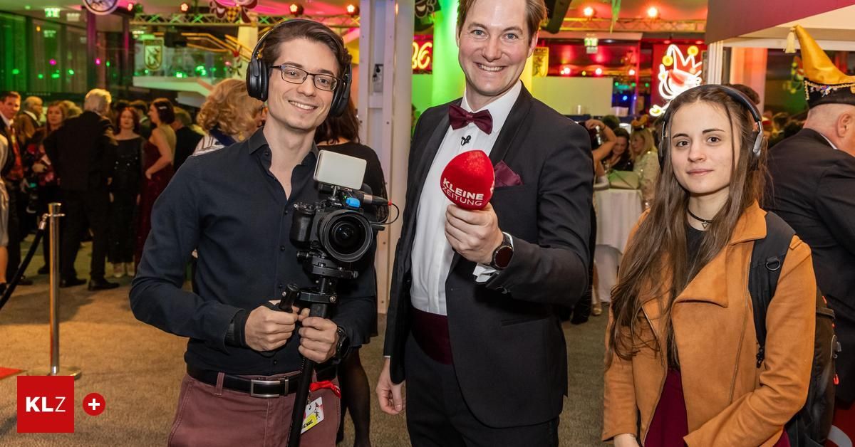 Drei Personen posieren für ein Foto bei einer formellen Veranstaltung. Der Mann auf der linken Seite trägt Kopfhörer und hält eine Kamera. Der Mann in der Mitte hält ein Mikrofon. Die Frau auf der rechten Seite lächelt.