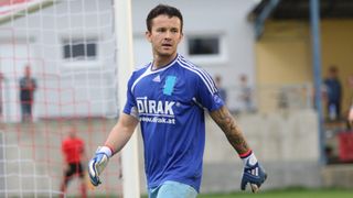 Ein Fußballspieler mit einem blauen Trikot läuft auf dem Feld. Er hat eine Tätowierung am Arm und schaut nach vorne.