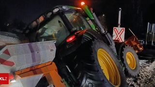 Ein Traktor mit rotem Licht und gelben Felgen steht nachts geparkt.