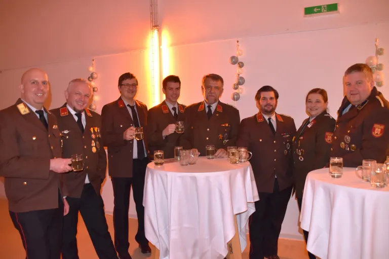 A group of people in military uniforms posing for a picture while holding glasses of beer at an event.