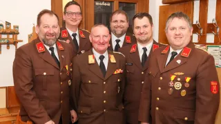 Eine Gruppe von sechs Männern in Militäruniformen steht zusammen. Sie alle lächeln und scheinen für ein Foto zu posieren.