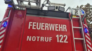 Ein rotes Notfallfahrzeug zeigt 'FEUERWEHR NOTRUF 122'. Es hat ein Lenkrad, Lichter und eine Leiter.