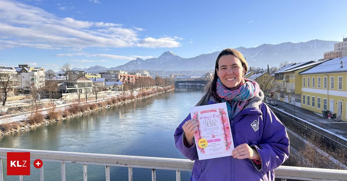 Eine Frau in einer lila Jacke hält ein Zertifikat mit den Worten Women's Day Frauen Messe. Hinter ihr befindet sich ein Fluss mit Bergen im Hintergrund.