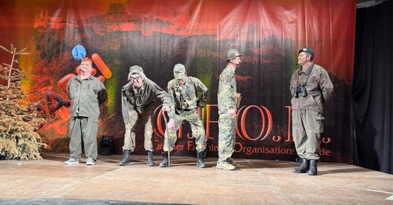 Fünf Männer in Militäruniformen stehen auf der Bühne. Sie schauen in eine Richtung. Ein Banner hinter ihnen trägt die Aufschrift 'Greener Farming' und 'Organisations'.