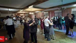Ein formeller Tanzabend mit älteren Erwachsenen beim Tanzen, einem Mann in Uniform und einer Kronleuchter.
