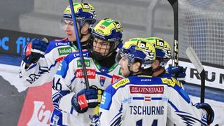 Eine Gruppe von Hockeyspielern mit Helmen und Trikots feiert auf dem Eis. Sie halten Eishockeyschläger in der Hand und schauen sich etwas an. Der Spieler in der Mitte trägt ein Trikot mit dem Wort Generali.
