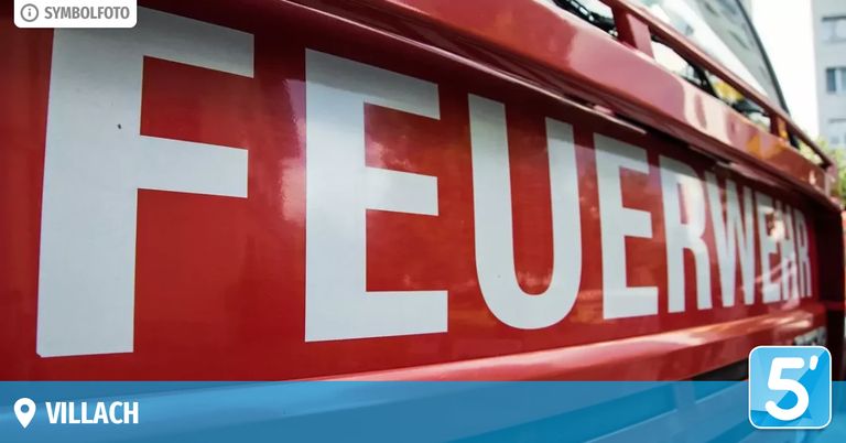Eine Nahaufnahme eines roten Feuerwehrwagens mit weißen Buchstaben, die 'FEUE' lesen, was darauf hinweist, dass es sich um einen Feuerwehrwagen handelt.