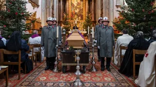 Eine Beerdigungszeremonie findet in einer Kirche statt mit einem Sarg, Kerzen und Menschen in Uniform.