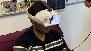 Ein Mann mit einer Syntropic-Virtual-Reality-Brille sitzt auf einem Stuhl, möglicherweise in einem medizinischen oder Forschungsumfeld.