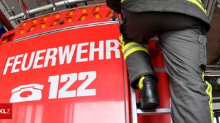 Ein Feuerwehrmann klettert eine Leiter hinauf, die an einem Feuerwehrwagen befestigt ist, mit der Nummer 122 auf der Seite sichtbar.