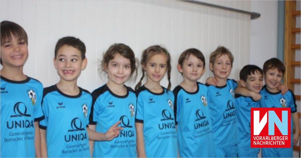 A group of children in matching blue sports jerseys with the word UNIQA on them, standing close together and smiling for a photo.