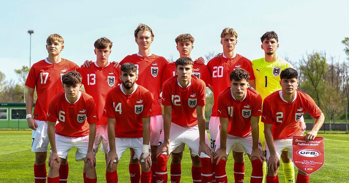 Eine Gruppe junger Fußballspieler in roten Trikots mit Nummern posiert für ein Foto auf einem Feld.
