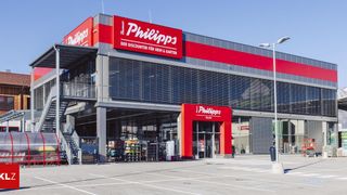 Ein modernes Ladengebäude mit einem roten Schild, das Philipps, einen Discounter für Haus und Garten, anzeigt.