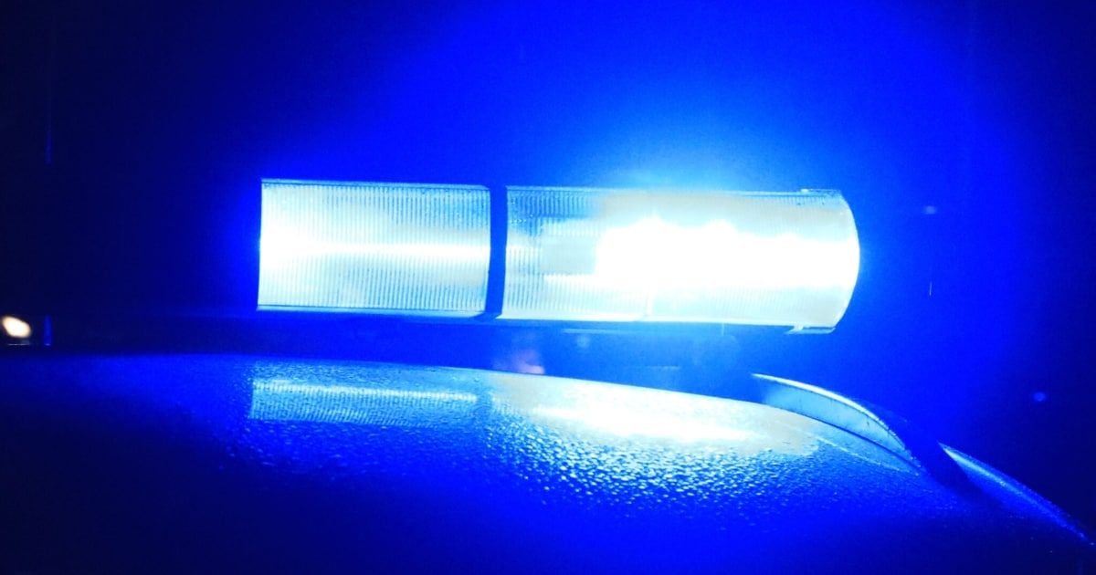 Nahaufnahme einer blauen Polizeilichtleiste auf einem Fahrzeug. Die Lichtleiste ist eingeschaltet und beleuchtet die Szene.