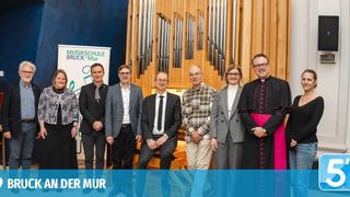 Eine Gruppe von Personen steht vor einer Orgel. Sie scheinen sich bei einer Veranstaltung zu befinden und lächeln für die Kamera. Ein Schild hinter ihnen lautet 'Musikschule Bruck an der Mur'.