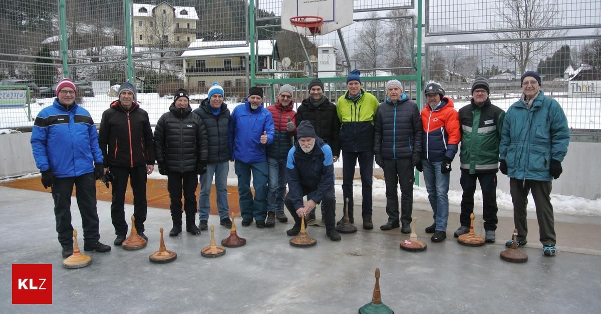 Eine Gruppe von Männern in Winterkleidung steht draußen mit Schnee am Boden. Sie sind um ein Set von Kegeln herum. Der Mann in der Mitte hockt sich hinunter.