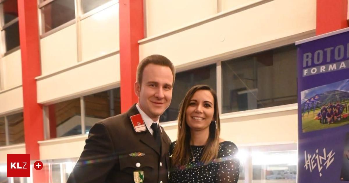 A man and a woman are standing together and smiling, likely at an event. They are both dressed formally.