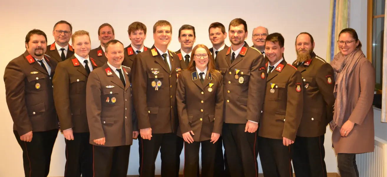 A group of uniformed individuals, including men and one woman, stand together for a photograph. They wear medals and badges on their uniforms.