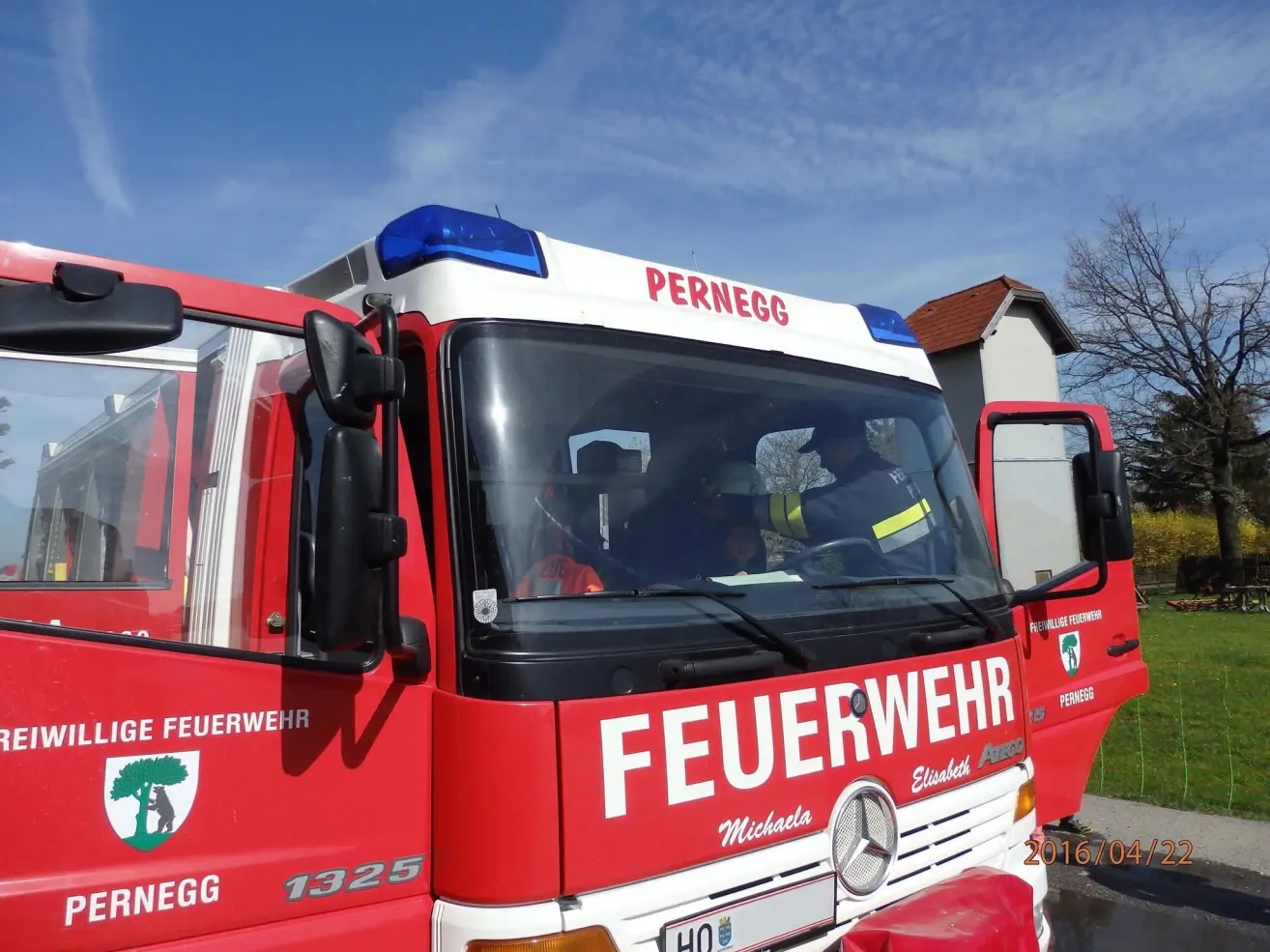 Ein roter Feuerwehrwagen mit der Aufschrift Pernegg auf der Oberseite und der Nummer 1325 auf der Seite. Er hat ein blaues Licht oben und ein Logo auf der Seite.
