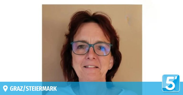 Eine Frau mit kurzen Haaren und Brille lächelt in die Kamera. Sie trägt ein weißes T-Shirt. Der Hintergrund ist hellbeige mit einem blauen Banner am unteren Rand mit dem Wort 'iermark'.