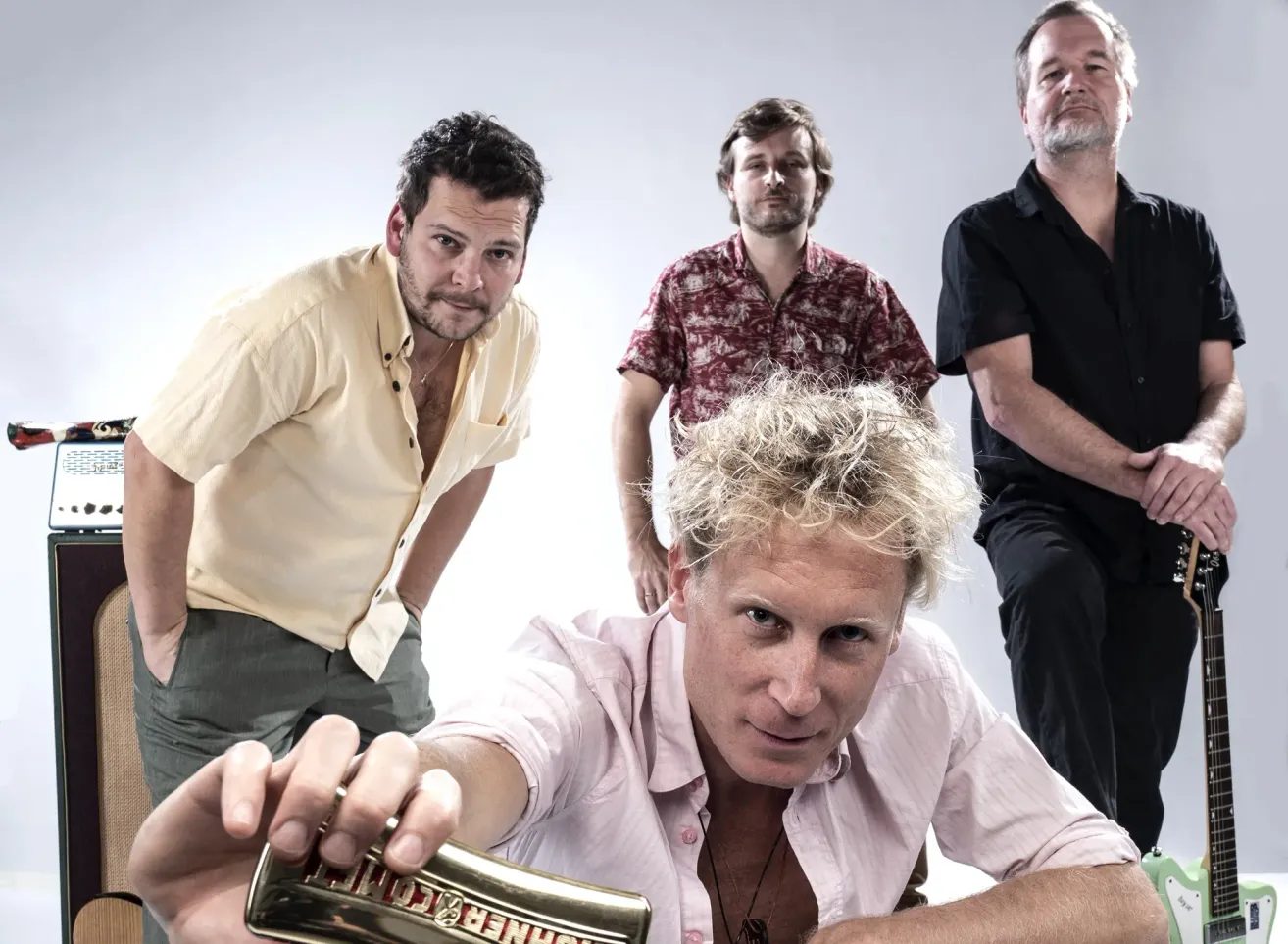 Vier Männer in Freizeitkleidung posieren für ein Foto. Ein Mann kniet und hält einen Pokal, während die anderen hinter ihm stehen.