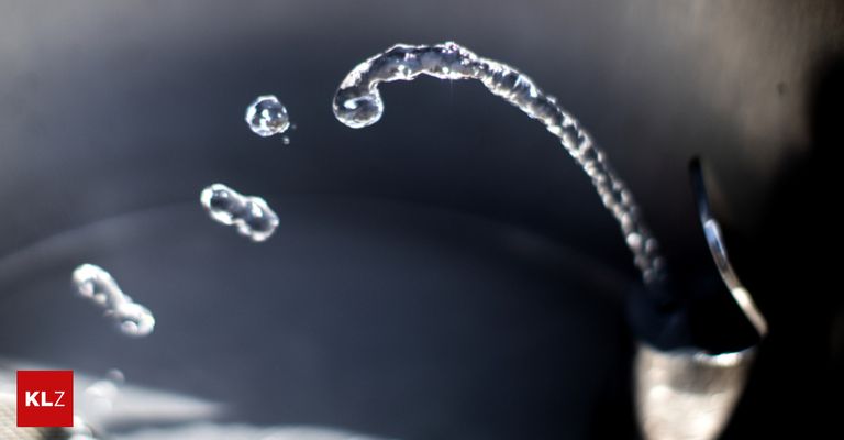 Eine Nahaufnahme von Wassertropfen, die aus einem Wasserhahn fließen, aufgenommen mit geringer Schärfentiefe.
