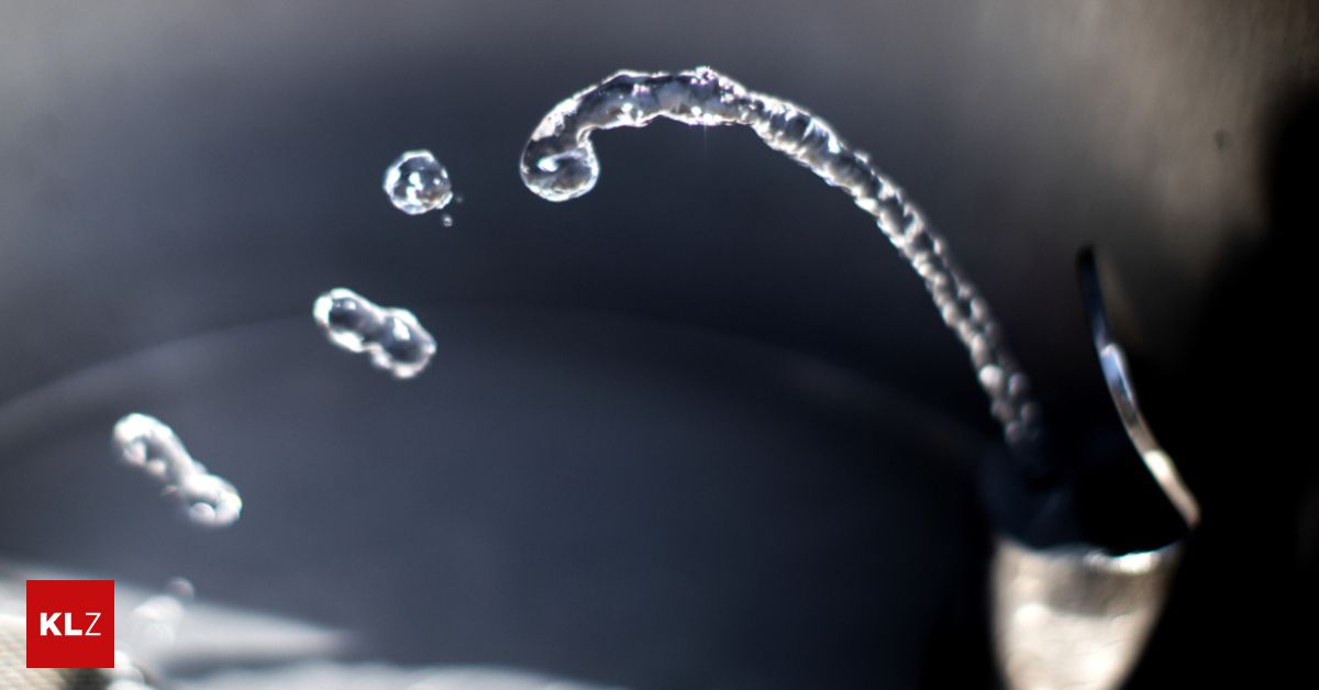 Eine Nahaufnahme von Wassertropfen, die aus einem Wasserhahn fließen, aufgenommen mit geringer Schärfentiefe.