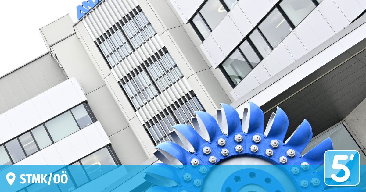 Ein großes weißes Gebäude mit dem Logo 'AN' oben. Das Gebäude hat viele Glasfenster. Vor dem Gebäude steht eine blaue Metallstruktur mit mehreren Bolzen.