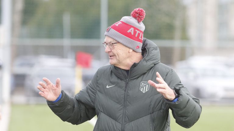Ein älterer Mann in einer grauen Jacke und einer Atlanta-Mütze steht auf einem Feld und gestikuliert mit den Händen.