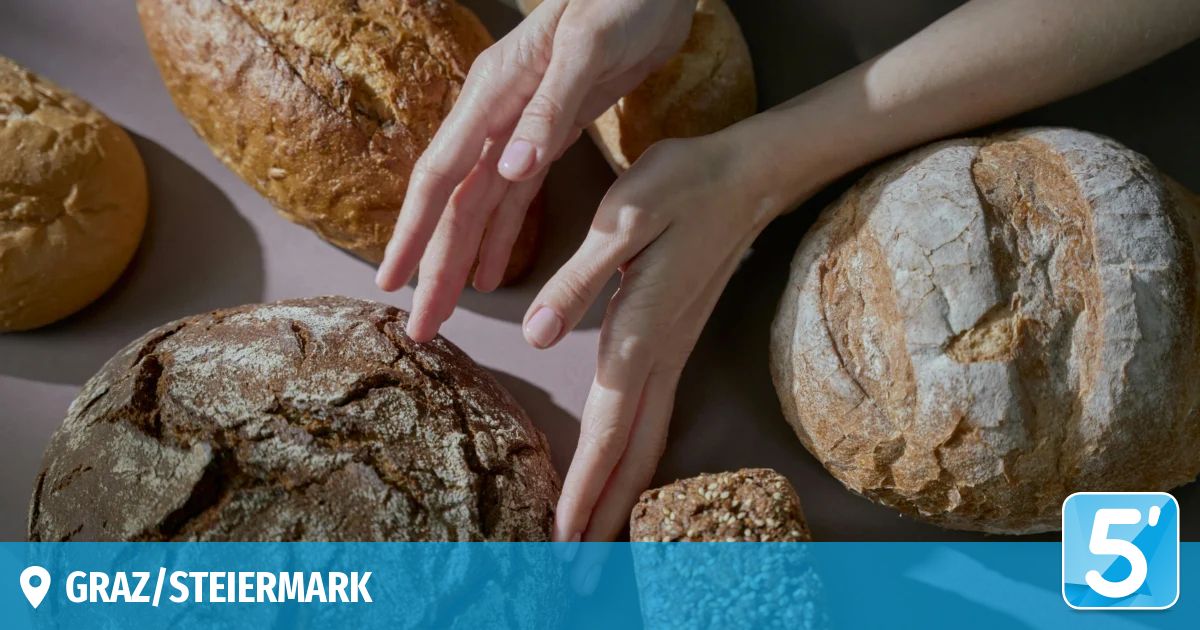Die Hände einer Person berühren verschiedene Arten von Brot auf einer weißen Oberfläche, möglicherweise in Vorbereitung auf das Backen oder Essen. Die Brote haben unterschiedliche Formen und Texturen.