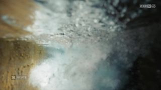 Eine Nahaufnahme einer nassen Oberfläche, möglicherweise durch Regen, mit einer Mischung aus Grau- und Blautönen und kleinen Wassertropfen.