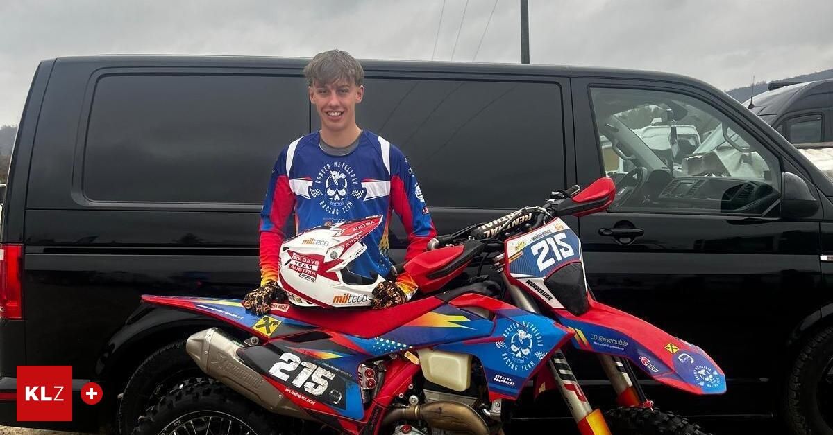 Ein junger Mann steht neben einem roten und blauen Motorrad mit der Nummer 215. Er trägt einen Helm und Handschuhe. Hinter ihm steht ein schwarzer Van.