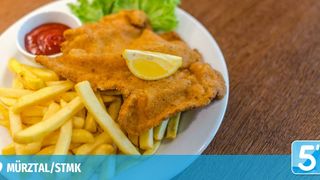Ein Teller mit gebratenem Fisch mit einer Zitronenscheibe, serviert mit Pommes Frites und einer Schüssel Ketchup.