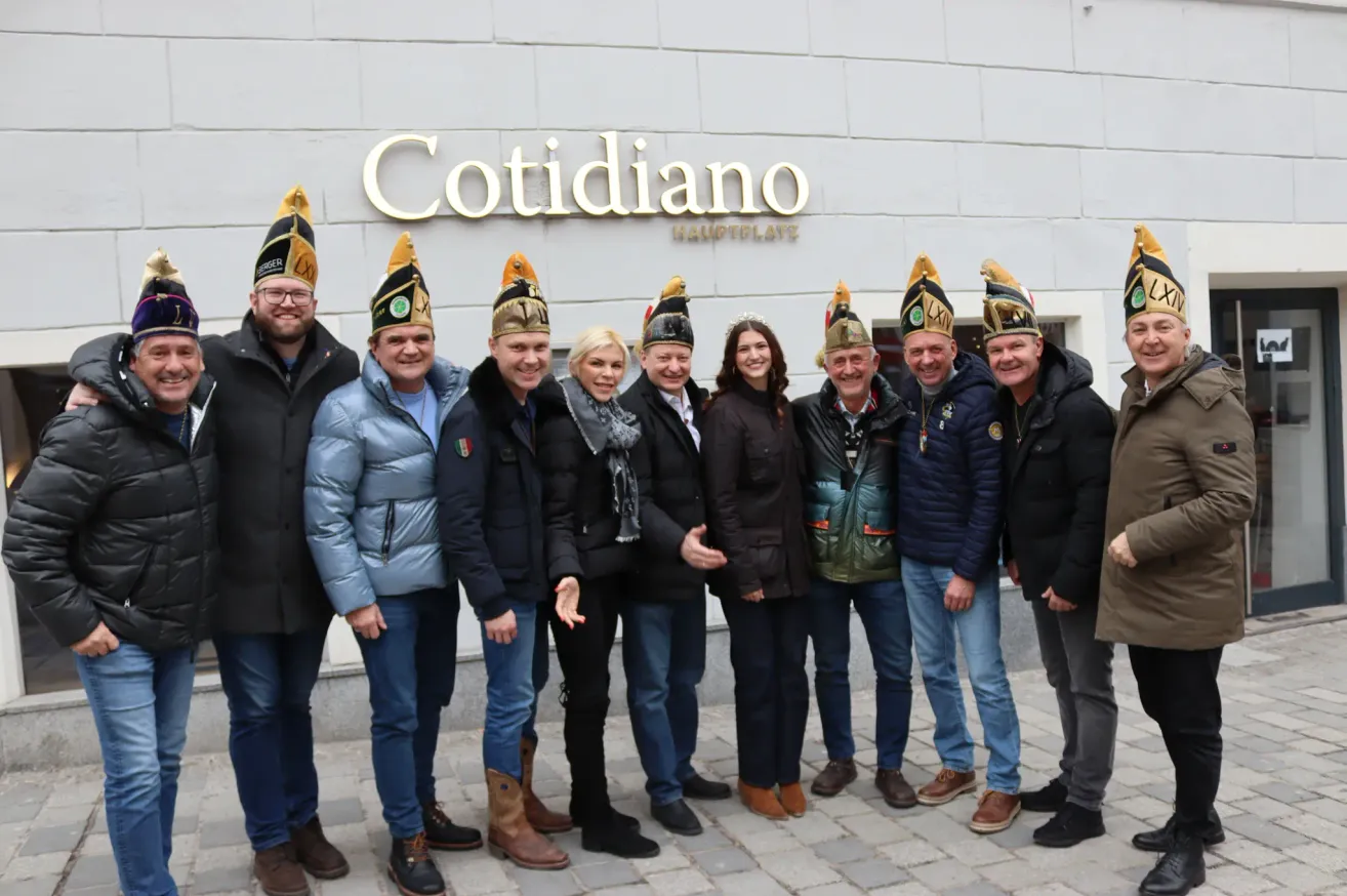 Eine Gruppe von Menschen in Winterkleidung posiert für ein Foto vor einem Gebäude mit dem Schild Cotidiano.