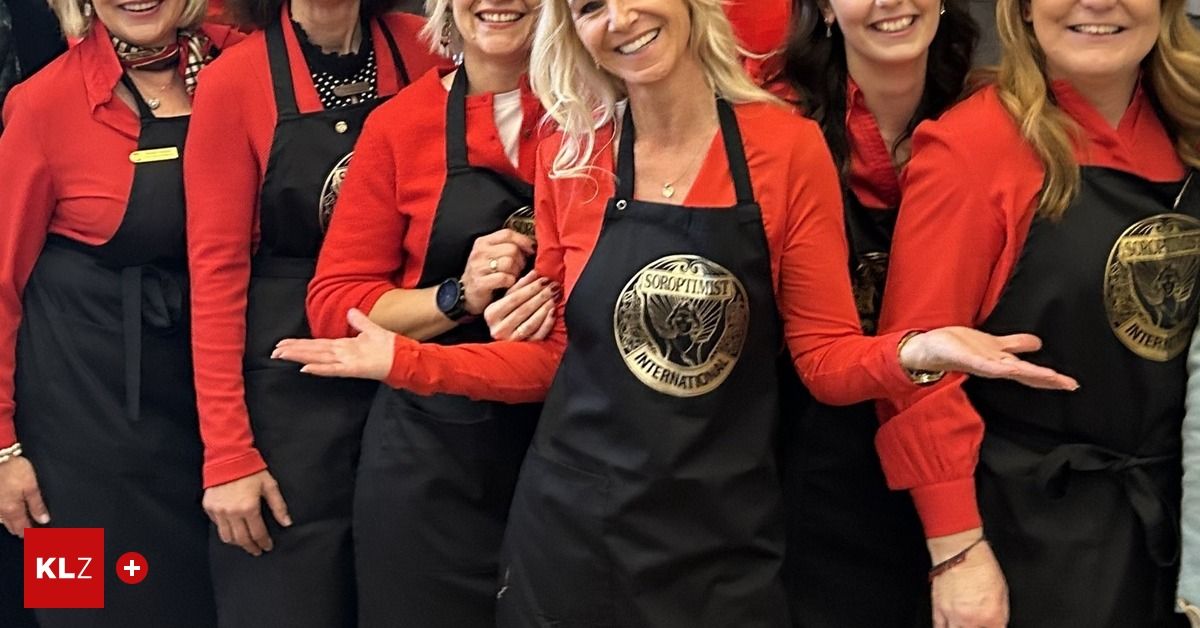 Eine Gruppe von Frauen in roten Langarmshirts und schwarzen Schürzen, eine mit dem Logo 'SOROPTIST INTERNATIONAL', lächelt und posiert für ein Foto.