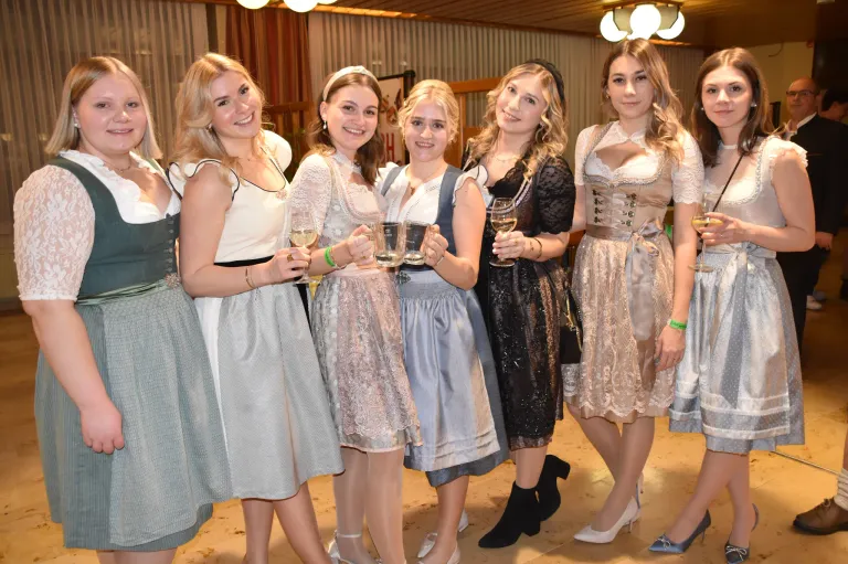 Eine Gruppe von Frauen in traditioneller Kleidung, möglicherweise für ein Fest, posiert für ein Foto mit Weingläsern in der Hand. Sie lächeln für die Kamera und vermitteln eine festliche Atmosphäre.