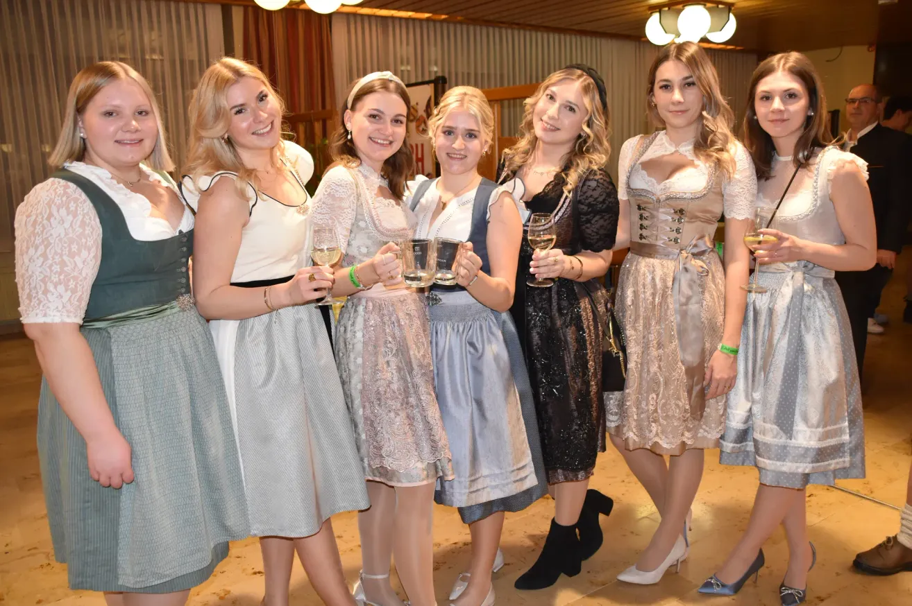 Eine Gruppe von Frauen in traditioneller Kleidung, möglicherweise für ein Fest, posiert für ein Foto mit Weingläsern in der Hand. Sie lächeln für die Kamera und vermitteln eine festliche Atmosphäre.