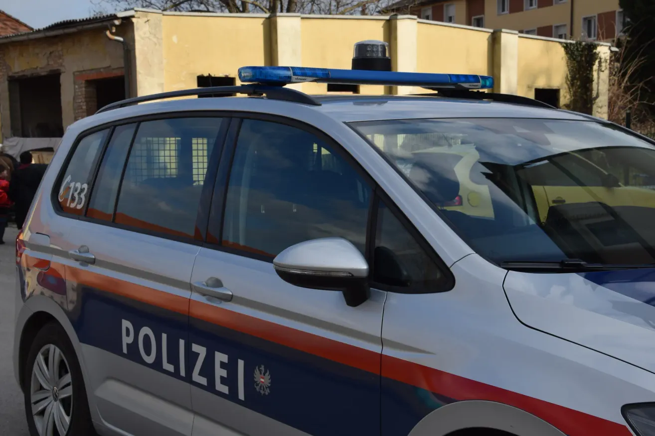 A police vehicle with a blue light on top is parked in front of a yellow building.