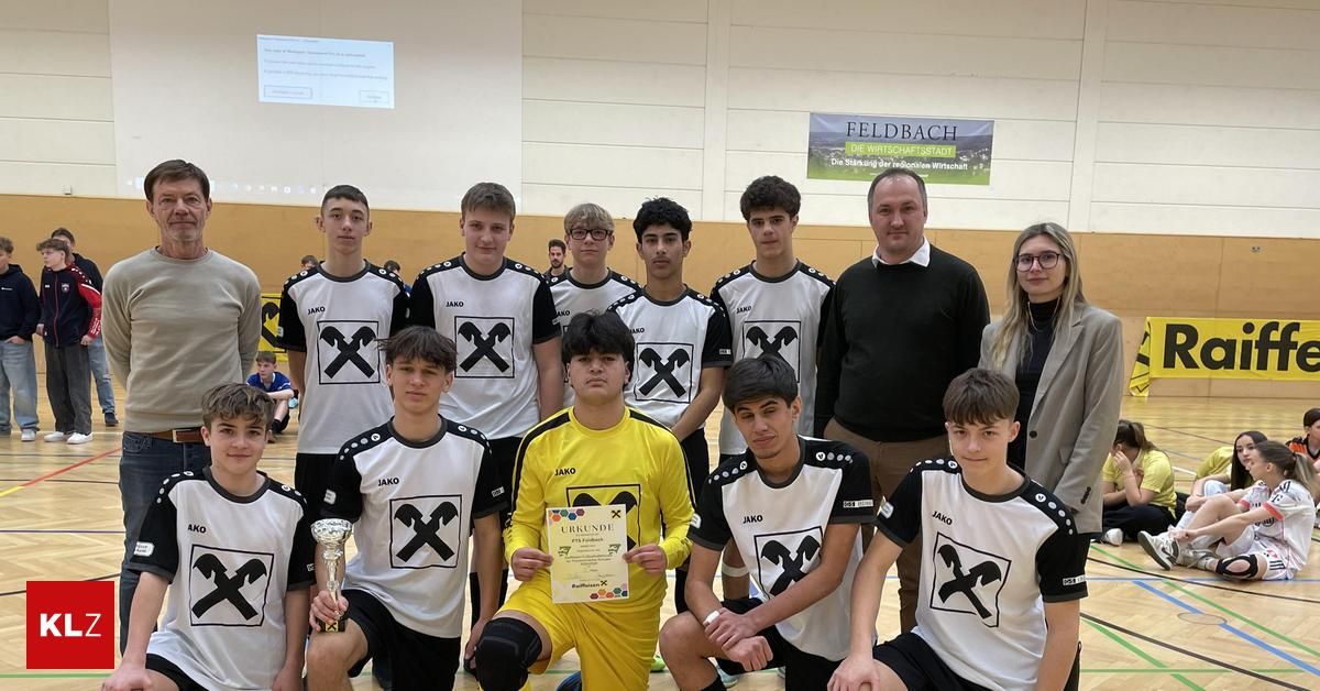 A sports team wearing white and black jerseys with the letter 'X' poses for a picture with a man holding a trophy and a certificate. They are in a gym with a banner in the background.