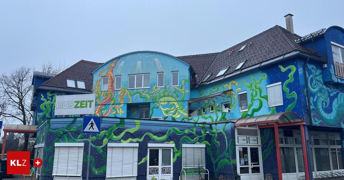 A building with a mural of sea creatures and tentacles. There is a pedestrian crossing sign nearby.