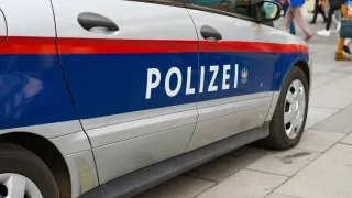 A white and blue police car is parked on the side of the road. The word 'POLIZEI' is written in white on the side.
