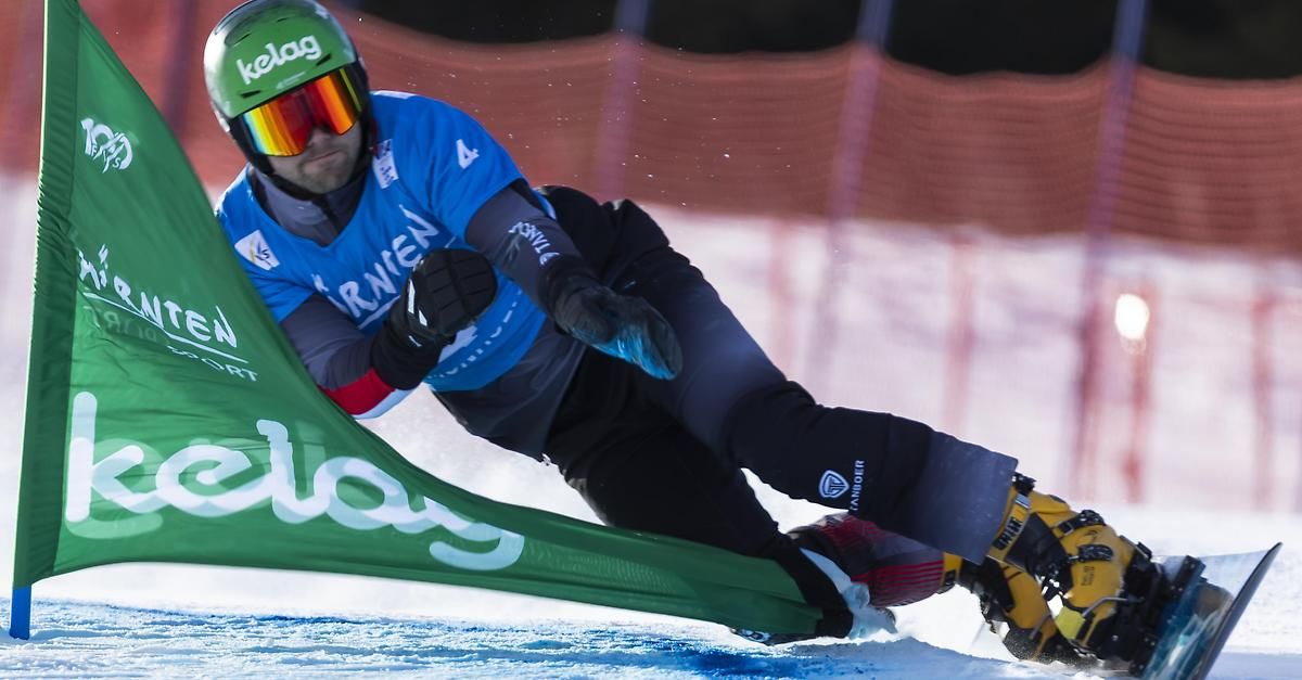 A skier is sliding on the snow, wearing a green helmet, goggles, and ski gear, and holding a banner with the word 'slalom'.