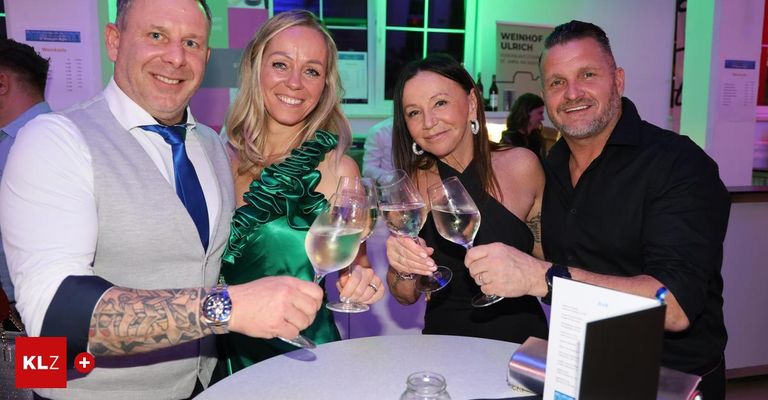 Vier Personen lächeln und posieren für ein Foto bei einer Veranstaltung. Zwei Frauen halten Weingläser in der Hand. Der Mann auf der linken Seite hat eine Tätowierung am Arm und der Mann auf der rechten Seite trägt eine Uhr. Hinter ihnen befindet sich ein Banner mit dem Text Weinhof Ulrich.