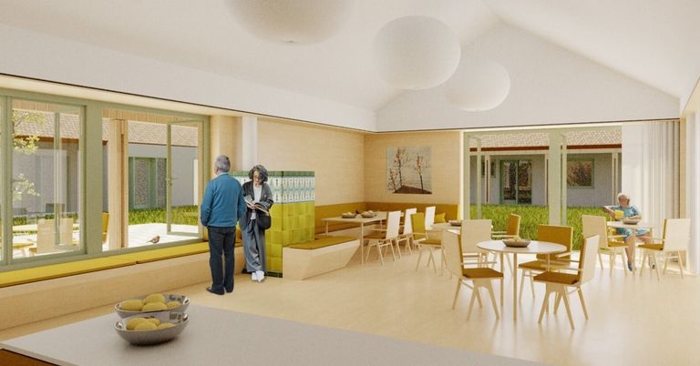 Eine Innenszene mit zwei Personen, eine liest, nahe einer Glastür. Ein Essbereich mit Tischen, Stühlen und einer Bank. Kunst an der Wand, runde Lampen an der Decke.